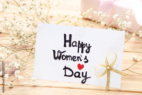 Text Happy Women's Day with gypsophila flowers on brown wooden table