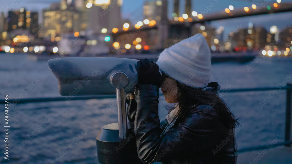 Young woman looks through a spyglass at Brooklyn Bridge New York Young woman looks through a spyglass at Brooklyn Bridge New York