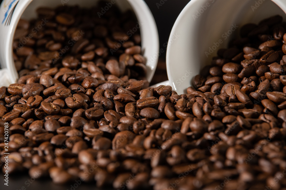 white cups with a pattern and grains of coffee on a black background white cups with a pattern and grains of coffee on a black background