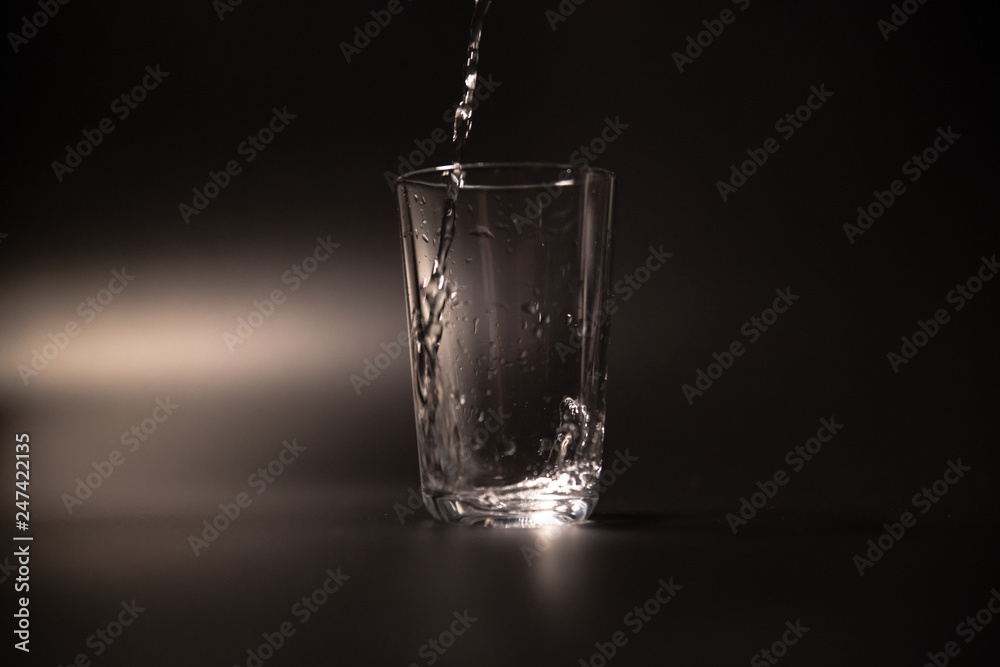 On a black background in a glass of water poured On a black background in a glass of water poured