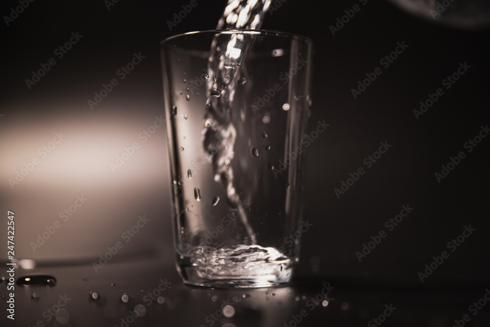 On a black background in a glass of water poured On a black background in a glass of water poured