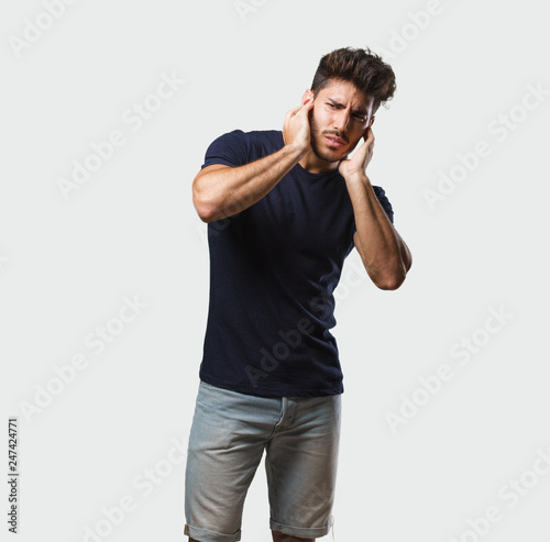Young handsome man standing covering ears with hands, angry and tired of hearing some sound