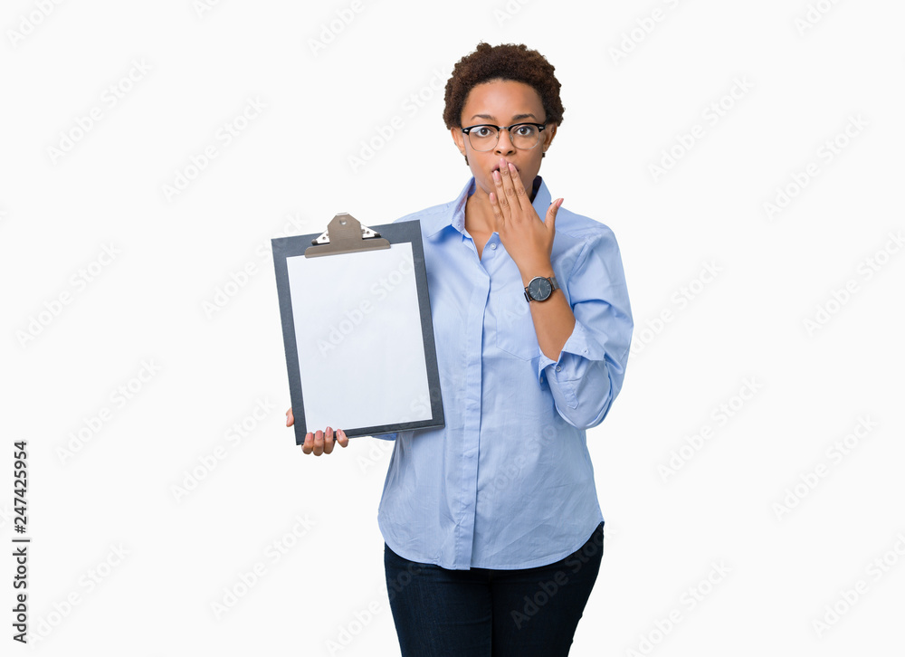 Young african american businesss woman holding clipboard over isolated background cover mouth with hand shocked with shame for mistake, expression of fear, scared in silence, secret concept Young african american businesss woman holding clipboard over isolated background cover mouth with hand shocked with shame for mistake, expression of fear, scared in silence, secret concept