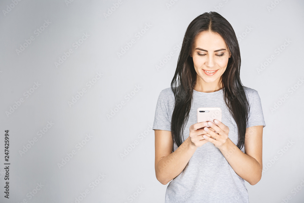 Portrait of a happy young woman using mobile phone isolated over white background.