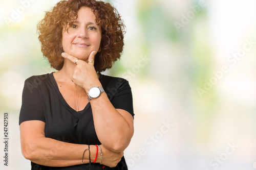 Beautiful middle ager senior woman over isolated background looking confident at the camera with smile with crossed arms and hand raised on chin. Thinking positive.