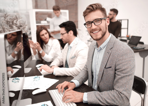 smiling businessman uses a computer to analyze financial data