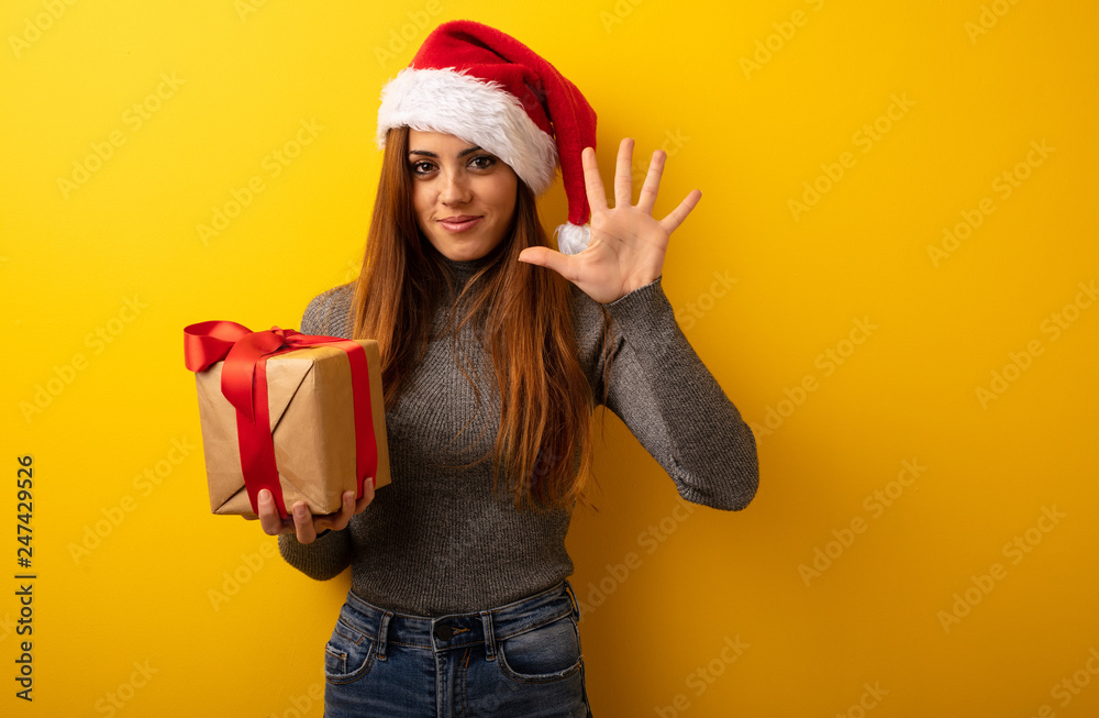 Young pretty woman holding gift showing number five Young pretty woman holding gift showing number five