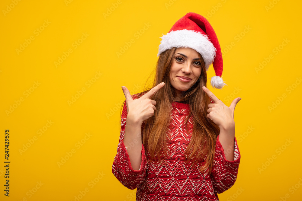 Young woman wearing santa hat smiles, pointing mouth Young woman wearing santa hat smiles, pointing mouth