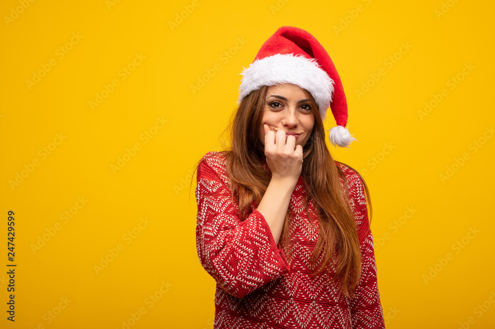 Young woman wearing santa hat biting nails, nervous and very anxious Young woman wearing santa hat biting nails, nervous and very anxious