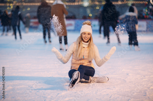 Young smiling woman with skates on the ice rink