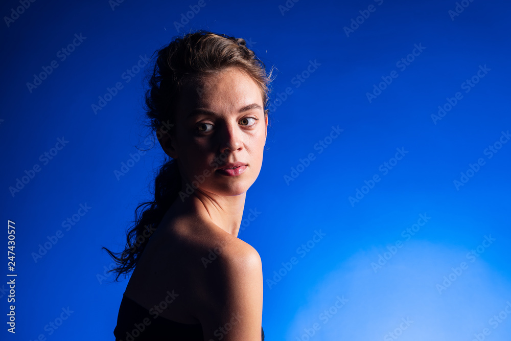 Beautiful woman with brunette long curly hair. Beauty portrait of modern fashion, blue background.