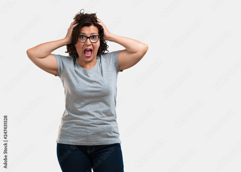 Middle aged woman frustrated and desperate, angry and sad with hands on head Middle aged woman frustrated and desperate, angry and sad with hands on head