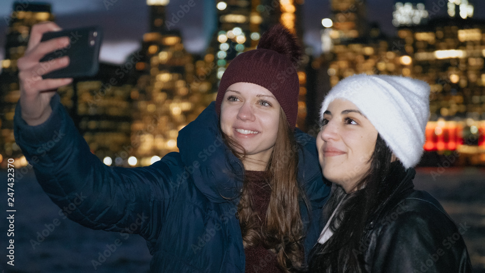 Two girls enjoy a wonderful night in New York in front of the Manhattan skyline