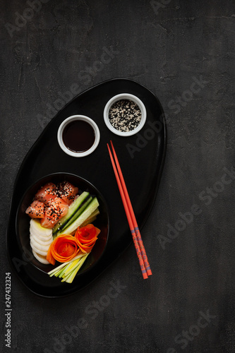 Colorful Asian trendy food, sushi poke bowl with cucumber, salmon, carrot, avocado, Sesame Seeds and soy sauce. Top view, close up