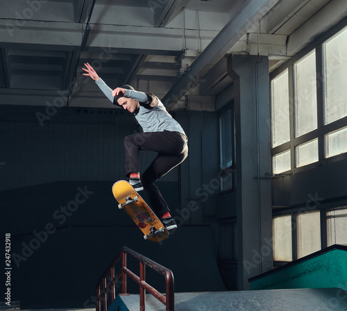 Fotografie, Obraz Skateboarder jumping high on mini ramp at skate park indoor.