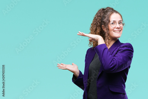 Young brunette student girl wearing school uniform and glasses over isolated background gesturing with hands showing big and large size sign, measure symbol. Smiling looking at the camera