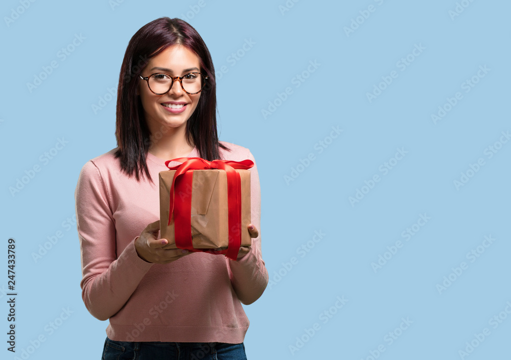 Young pretty woman happy and smiling, holding a nice gift, excited and full, celebrating a birthday or a featured event Young pretty woman happy and smiling, holding a nice gift, excited and full, celebrating a birthday or a featured event
