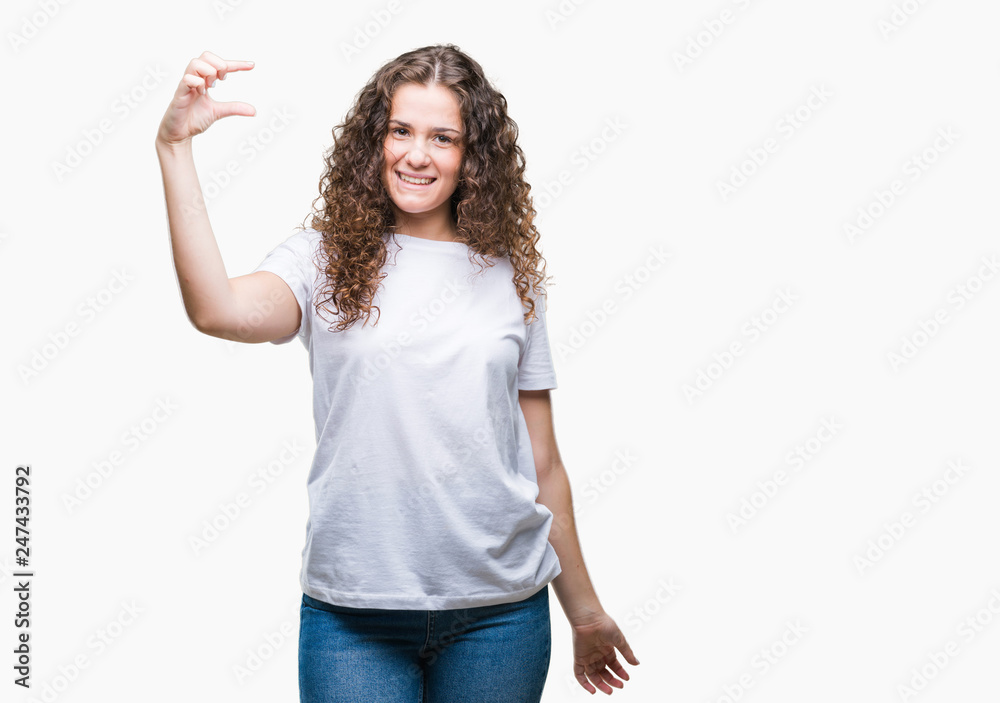 Beautiful brunette curly hair young girl wearing casual t-shirt over isolated background smiling and confident gesturing with hand doing size sign with fingers while looking and the camera Beautiful brunette curly hair young girl wearing casual t-shirt over isolated background smiling and confident gesturing with hand doing size sign with fingers while looking and the camera