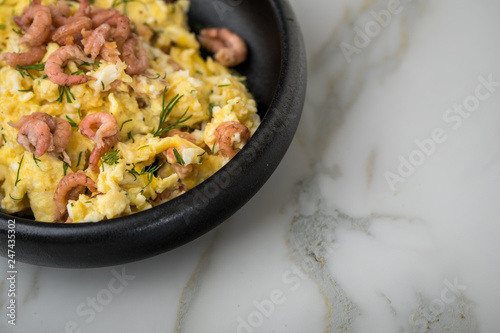 Krabben Rührei mit Friesischen Nordseekrabben und Dill in schwarzer Schale auf Marmor Hintergrund