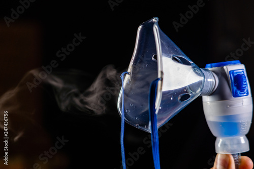 mask nebulizer produces a pair of drugs on a dark background. close-up of face mask photo