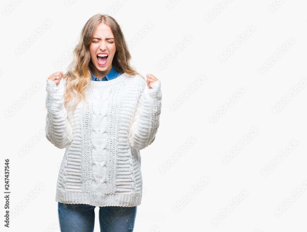 Beautiful young blonde woman wearing winter sweater over isolated background excited for success with arms raised celebrating victory smiling. Winner concept. Beautiful young blonde woman wearing winter sweater over isolated background excited for success with arms raised celebrating victory smiling. Winner concept.