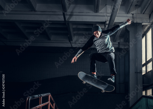 Skateboarder jumping high on mini ramp at skate park indoor. photo