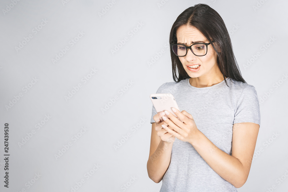 Oh no! Really? Shocked young woman looking at mobile phone reading news, wearing casual, isolated on white background. Oh no! Really? Shocked young woman looking at mobile phone reading news, wearing casual, isolated on white background.