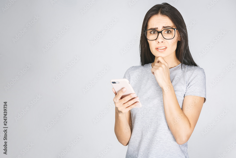 Oh no! Really? Shocked young woman looking at mobile phone reading news, wearing casual, isolated on white background. Oh no! Really? Shocked young woman looking at mobile phone reading news, wearing casual, isolated on white background.
