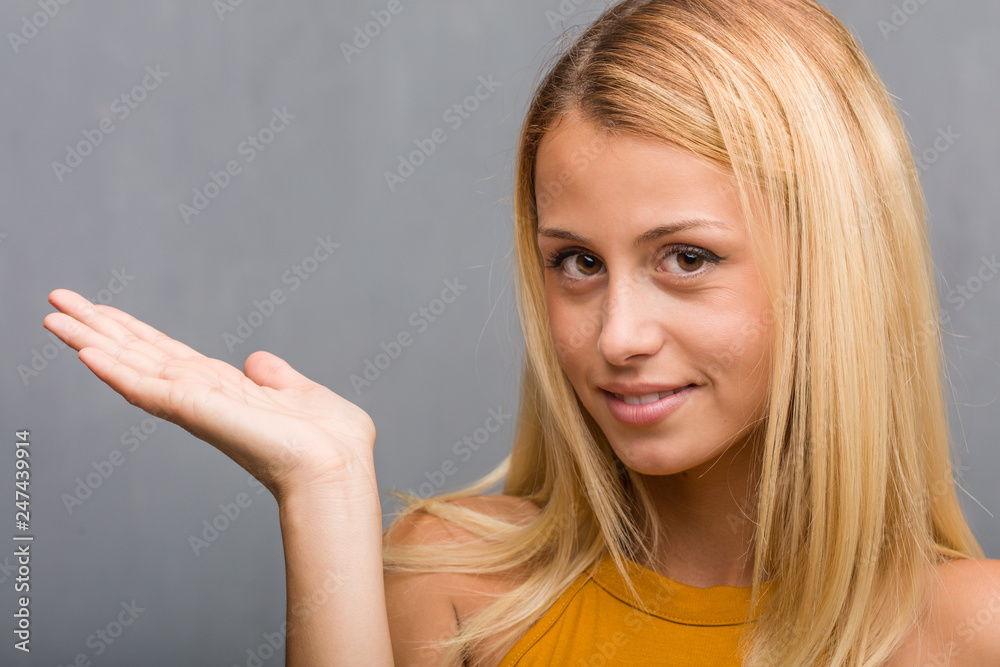 Face closeup, portrait of a natural young blonde woman holding something with hands, showing a product, smiling and cheerful, offering an imaginary object Face closeup, portrait of a natural young blonde woman holding something with hands, showing a product, smiling and cheerful, offering an imaginary object