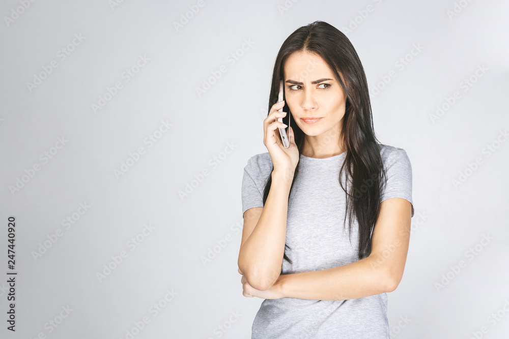 Image of sad angry young woman talking by mobile phone. Isolated over white background. Image of sad angry young woman talking by mobile phone. Isolated over white background.