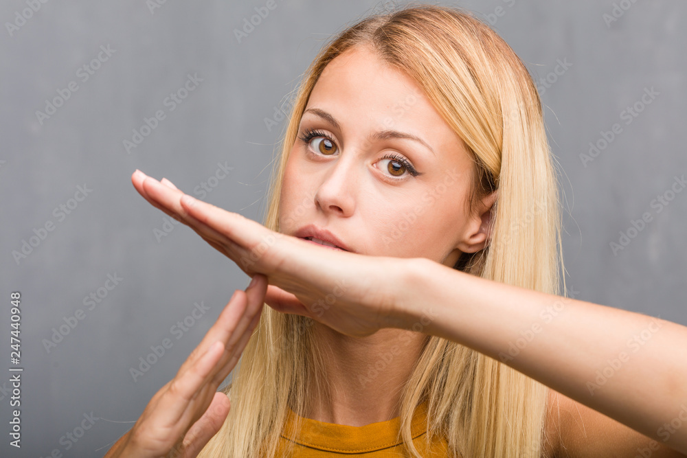 Face closeup, portrait of a natural young blonde woman tired and bored, making a timeout gesture, needs to stop because of work stress, time concept Face closeup, portrait of a natural young blonde woman tired and bored, making a timeout gesture, needs to stop because of work stress, time concept
