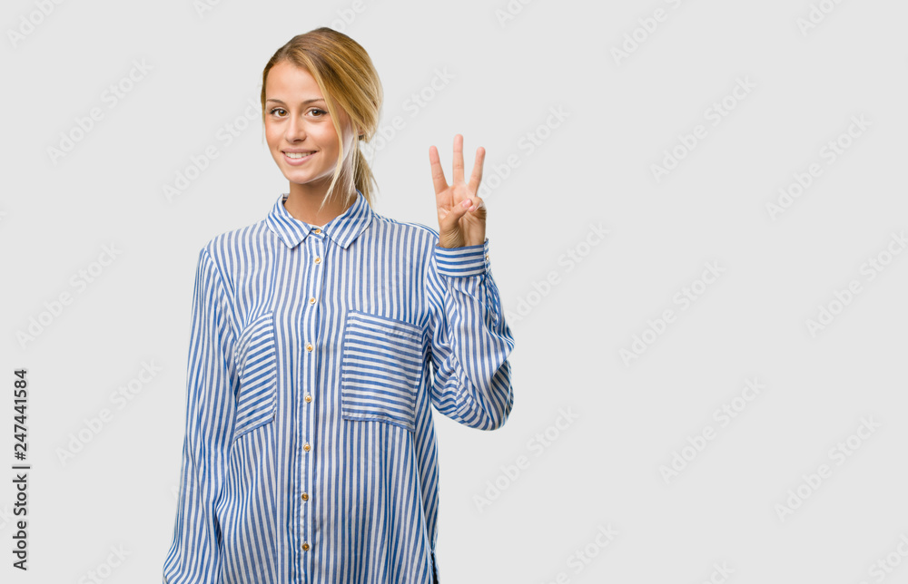 Portrait of a young pretty blonde woman showing number three, symbol of counting, concept of mathematics, confident and cheerful Portrait of a young pretty blonde woman showing number three, symbol of counting, concept of mathematics, confident and cheerful
