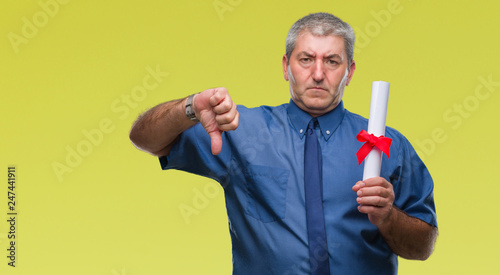 Handsome senior man holding degree over isolated background with angry face, negative sign showing dislike with thumbs down, rejection concept