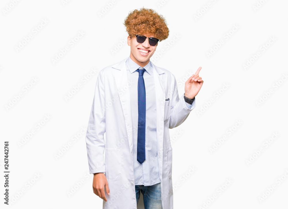 Young handsome scientist man wearing professional coat and sunglasses with a big smile on face, pointing with hand and finger to the side looking at the camera. Young handsome scientist man wearing professional coat and sunglasses with a big smile on face, pointing with hand and finger to the side looking at the camera.