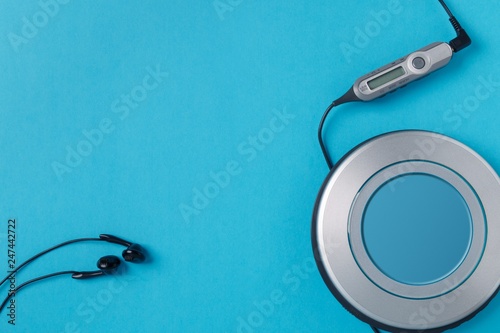 personal cd player with remote control and portable audio earphones on blue background