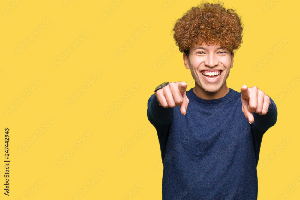 Young handsome man with afro hair Pointing to you and the camera with fingers, smiling positive and cheerful
