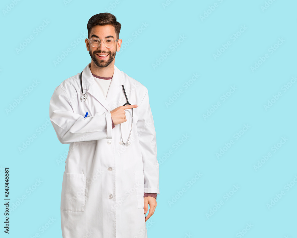 Young doctor man smiling and pointing to the side Young doctor man smiling and pointing to the side
