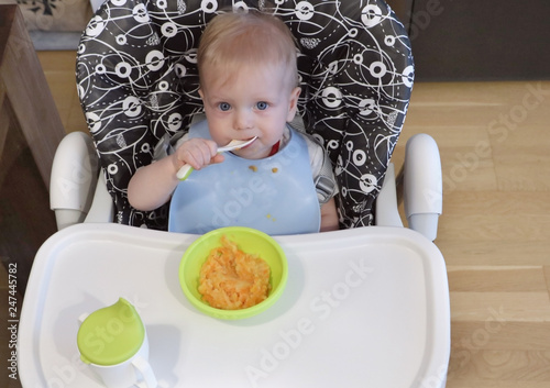 First year baby is eating first food with spoon