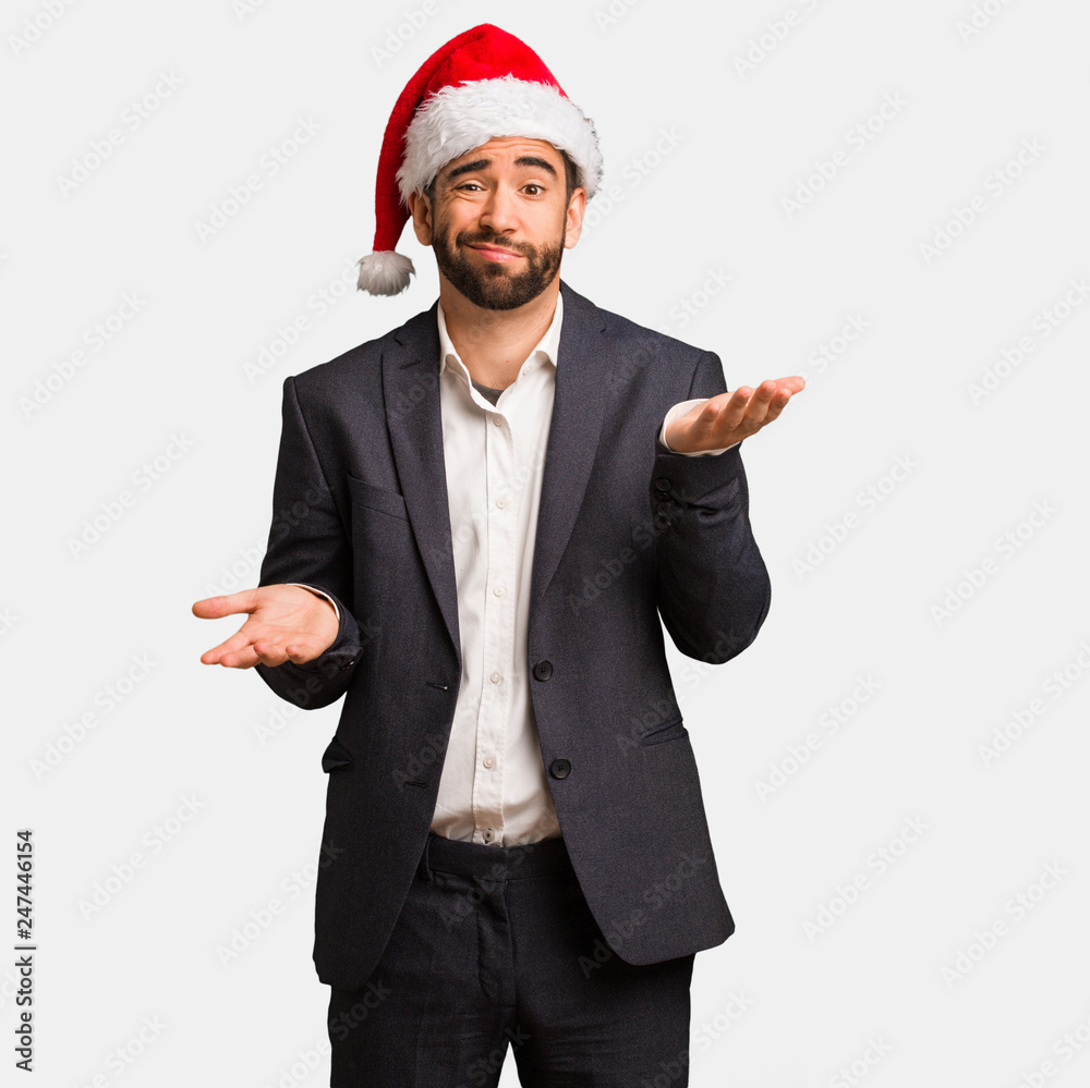 Young business man wearing santa hat confused and doubtful Young business man wearing santa hat confused and doubtful