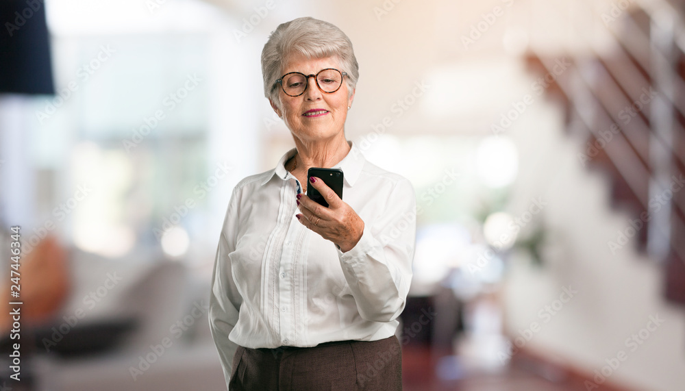 Beautiful senior woman closeup of hand touching a mobile, using internet and social networks, positive feeling of future and modernity at home. Beautiful senior woman closeup of hand touching a mobile, using internet and social networks, positive feeling of future and modernity at home.