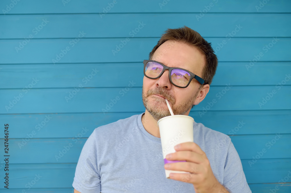 Portrait of a beautiful Mature man drinking a drink outdoors in summer. Portrait of a beautiful Mature man drinking a drink outdoors in summer.