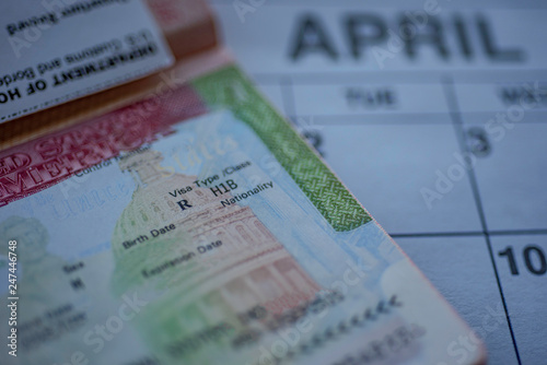 H1B visa (for specialty workers) stamp in passport, blurred april calendar on background. H1B visa program deadline concept. Close up view.