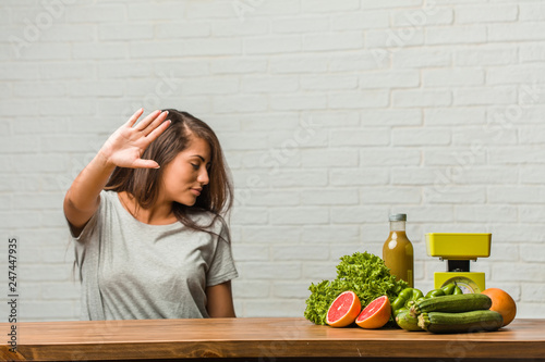 Concept of diet. Portrait of a healthy young latin woman serious and determined, putting hand in front, stop gesture, deny concept