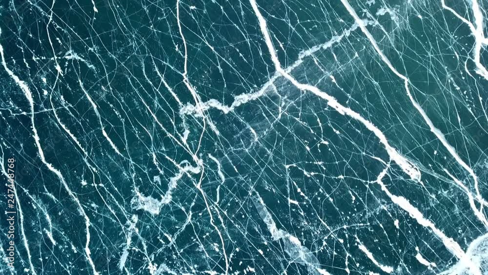 Drone rises above the frozen crystal ice of the lake Baikal. Top view. Natural background and patterns Drone rises above the frozen crystal ice of the lake Baikal. Top view. Natural background and patterns