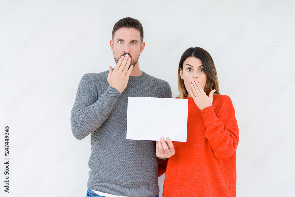 Young couple holding blank sheet paper over isolated background cover mouth with hand shocked with shame for mistake, expression of fear, scared in silence, secret concept Young couple holding blank sheet paper over isolated background cover mouth with hand shocked with shame for mistake, expression of fear, scared in silence, secret concept