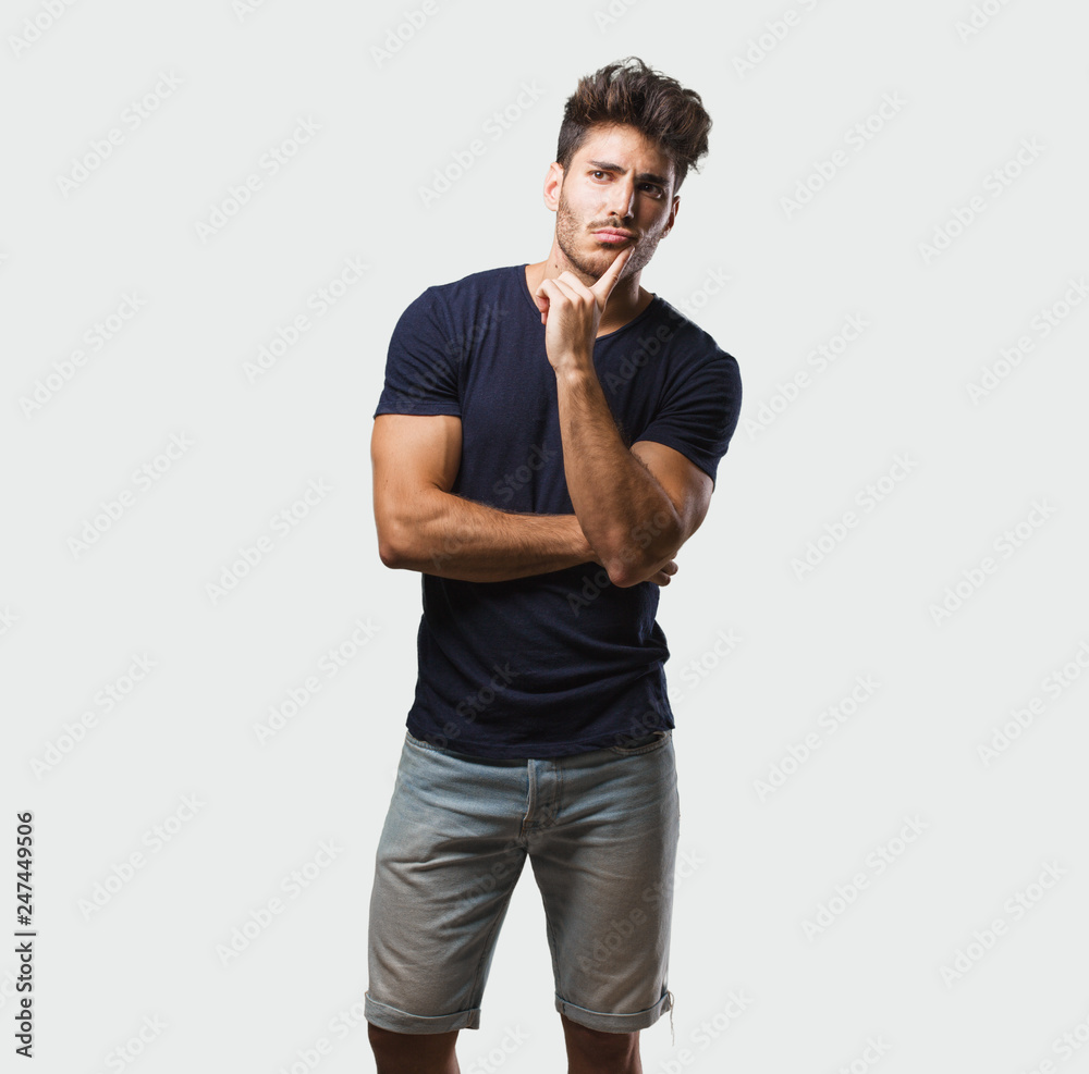Young handsome man standing doubting and confused, thinking of an idea or worried about something Young handsome man standing doubting and confused, thinking of an idea or worried about something
