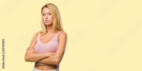 Portrait of young pretty blonde woman crossing his arms, serious and imposing, feeling confident and showing power