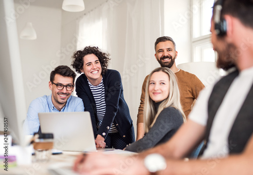 Bild auf Leinwand Group of young businesspeople around table in a modern office, having meeting