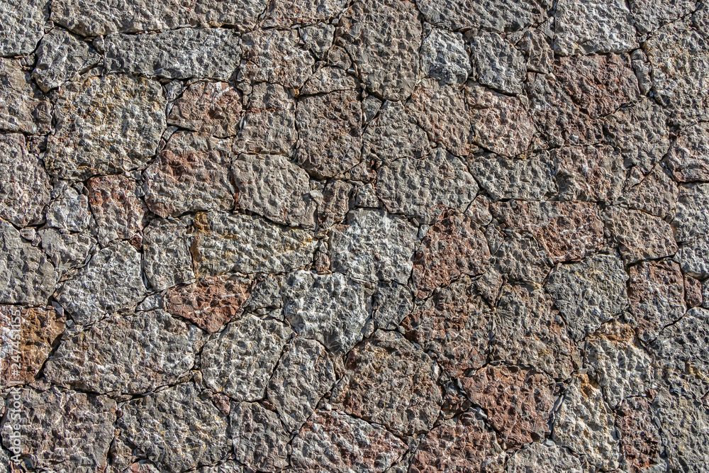 A beautiful texture of an old wall from gray and orange stones with cracks A beautiful texture of an old wall from gray and orange stones with cracks