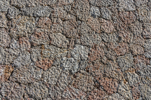 A beautiful texture of an old wall from gray and orange stones with cracks